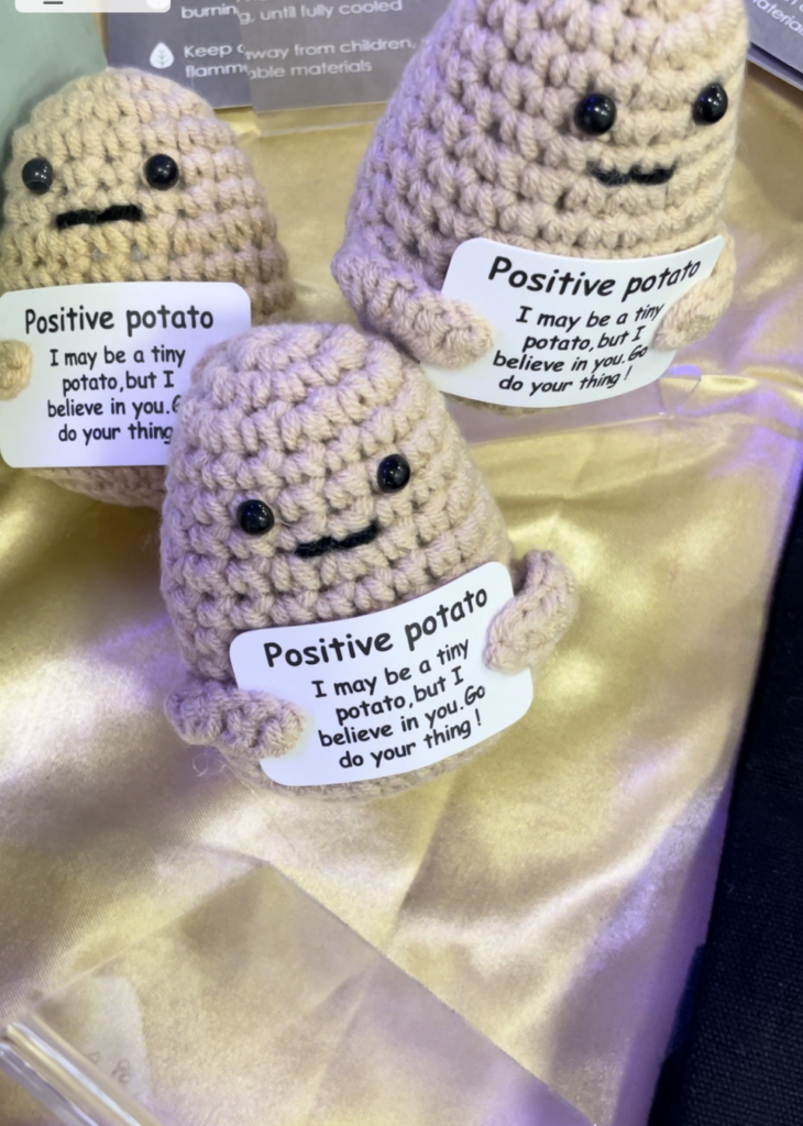 Knitted potato holding a sign saying "positive potato - I may be a tiny potato, but I believe in you.  Go do your thing !